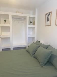 1 cama con almohadas verdes en una habitación blanca en Departamento céntrico Colón en Colón