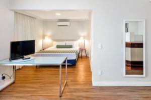 a bedroom with a bed and a desk with a television at Blue Tree Garden Bauru in Bauru