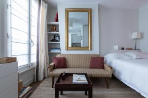 een slaapkamer met een bed, een bank en een spiegel bij Luxe Atelier bail mobilité Saint germain des Près in Parijs