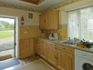 a kitchen with wooden cabinets and a sink and a window at Ashberry Cottage in Rievaulx