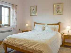 a bedroom with a large bed with two tables and two lamps at Tan-y-derwwen in Mydroilin