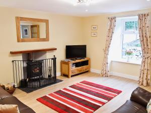 uma sala de estar com lareira e televisão em Longcroft Cottage - 28233 em Old Rayne