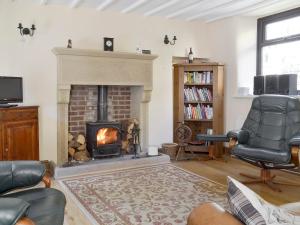 a living room with a fireplace and a chair at Poppy Cottage in Bonsall