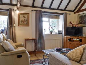 a living room with a couch and a tv at Bakery Cottage in Ampney Crucis