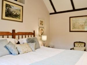 a bedroom with a white bed and a chair at Bakery Cottage in Ampney Crucis