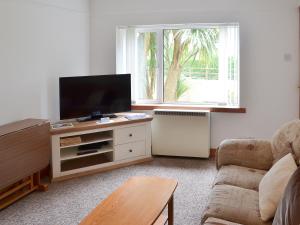 a living room with a flat screen tv and a couch at Copper Tree Cottage in Stokeinteignhead