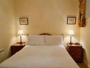 a bedroom with a large white bed with two lamps at Freesia Cottage-mjd in Akeld