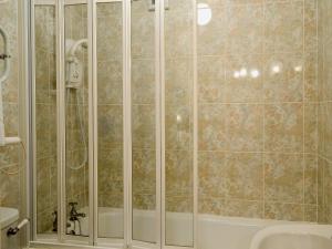 a shower with a glass door next to a sink at Freesia Cottage-mjd in Akeld