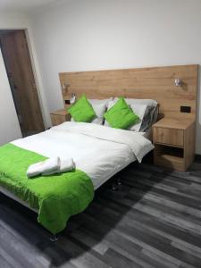 een slaapkamer met een groot bed met groene kussens bij Hotel Fénix Real Bogotá in Bogota