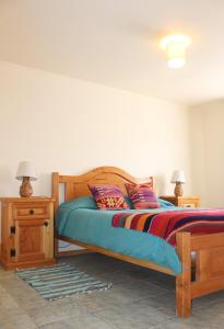 a bedroom with a wooden bed with two lamps and a table at Hostal Ayni in San Pedro de Atacama