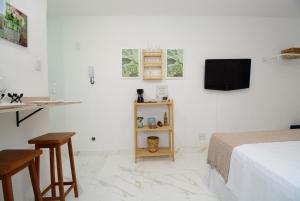 Habitación blanca con cama y TV en Petit Copa - Aconchego e praia!, en Río de Janeiro
