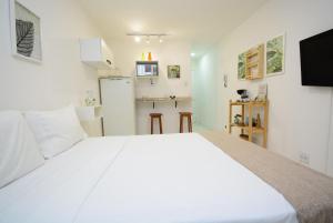1 cama blanca grande en una habitación con cocina en Petit Copa - Aconchego e praia!, en Río de Janeiro