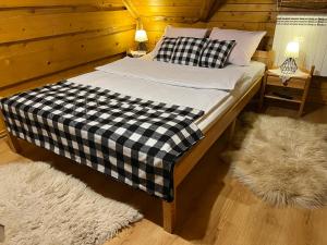 a bed with a black and white checkered sheets and pillows at Na Poddaszu - apartament na wyłączność in Kluszkowce