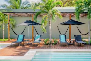 - un groupe de chaises longues et de parasols à côté de la piscine dans l'établissement Antelar Casa Destino, à Mérida