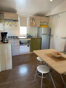 eine Küche mit einem Holztisch sowie einem Tisch und Stühlen in der Unterkunft Mobile home Sea Jezera Village, otok Murter in Tisno