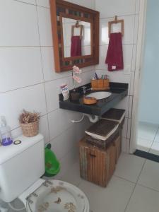 a bathroom with a sink and a toilet and a mirror at Chalé das Conchas in Cabo Frio