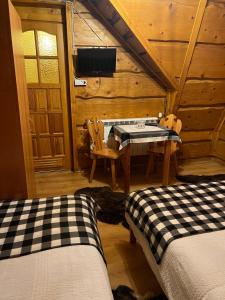a room with two beds and a table in a cabin at Na Poddaszu - apartament na wyłączność in Kluszkowce
