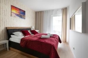 ein Schlafzimmer mit einem Bett mit einer roten Decke und einem Fenster in der Unterkunft Apartament SUNRISE Kudowa z balkonem in Kudowa-Zdrój