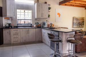 a kitchen with wooden cabinets and a counter with stools at 515 on Warthog by the River in Marloth Park