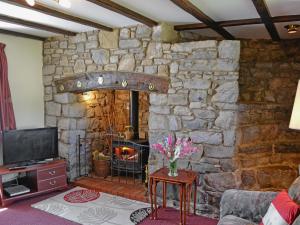 sala de estar con pared de piedra y chimenea en Murton Farm Cottage en Bishopston