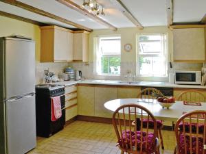 cocina con nevera, mesa y sillas en Murton Farm Cottage en Bishopston