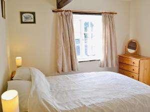 1 dormitorio con cama blanca y ventana en Granary Cottage - E5634, en Warkleigh