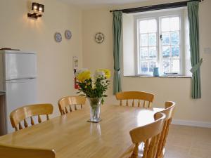 una mesa de comedor con un jarrón de flores. en Granary Cottage - E5634, en Warkleigh