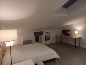 Dormitorio con cama, escritorio y TV en Studio mezzanine tout confort en Corny-sur-Moselle
