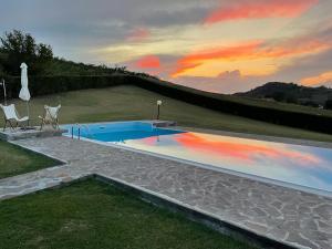 a swimming pool with two chairs and a sunset at Casa villetta "La Colomba" Nizza Monferrato in Nizza Monferrato