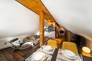 a living room with a table and yellow chairs at Cozy mountain attic apartment in High Tatras in Veľká Lomnica