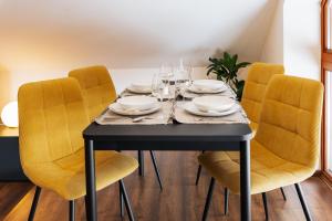 a dining room table with yellow chairs and a black table at Cozy mountain attic apartment in High Tatras in Veľká Lomnica