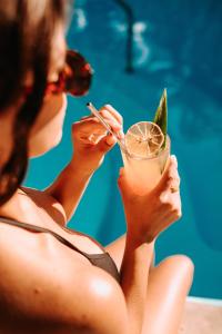 una mujer sentada junto a una piscina sosteniendo una bebida en Albatros Suites by Bedsfriends, en Cozumel