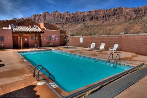 uma piscina com cadeiras e montanhas ao fundo em Prickly Pear Vista em Moab