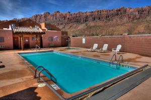 a swimming pool with chairs and a mountain in the background at Steel Bender Villa in Moab