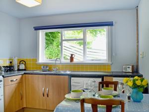 a kitchen with a table and a window at Kinnettas Cottage in Strathpeffer