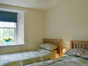 a bedroom with two beds and a window at Kinnettas Cottage in Strathpeffer