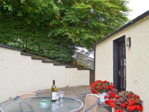 a table with a bottle of wine and some flowers at Kinnettas Cottage in Strathpeffer