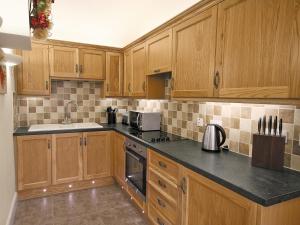 a kitchen with wooden cabinets and black counter tops at River Cottage - E5462 in Wainfleet All Saints