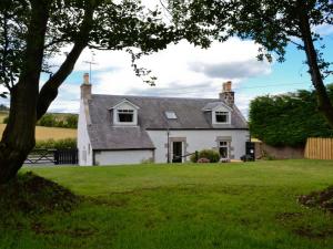 Una casa blanca con un árbol delante. en Longcroft Cottage - 28233, en Old Rayne