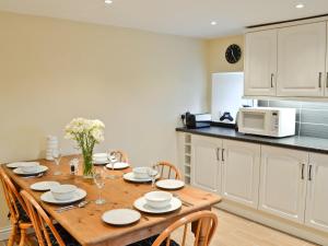 uma cozinha com uma mesa de madeira com cadeiras e um micro-ondas em Longcroft Cottage - 28233 em Old Rayne