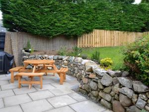 a wooden picnic table and a stone wall at Longcroft Cottage - 28233 in Oyne