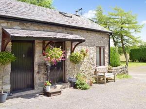 a stone cottage with a large door and a bench at Honeysuckle Cottage in Nerquis