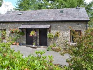 a stone house with flowers in front of it at Honeysuckle Cottage in Nerquis