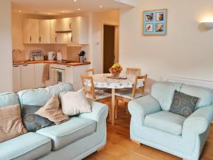 a living room with two couches and a table and a kitchen at The Old Stable in West Pennard