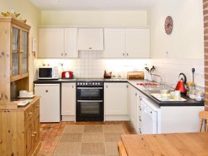 een keuken met witte kasten en een zwarte oven bij The Coach House in Yaxham