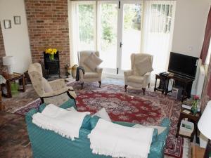 a living room with a couch and chairs and a television at The Coach House in Yaxham