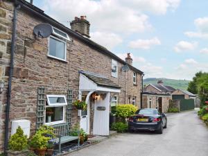 a brick house with a car parked in front of it at Golf Cottage in Chinley