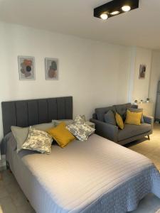 Una cama con almohadas amarillas y un sofá en una habitación en Hermoso Monoambiente en Santa Fe en Santa Fe