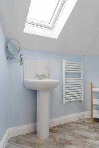 a white bathroom with a sink and a skylight at Fishermans Rest in Sheringham