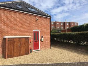 a brick garage with a red door and a red door at Fishermans Rest in Sheringham